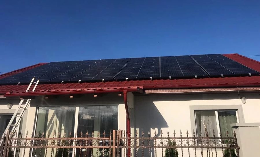 Panouri fotovoltaice montate pe acoperișul unei case, lângă terasă
